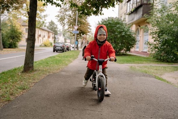 kisgyerek futóbiciklizik a kertvárosban